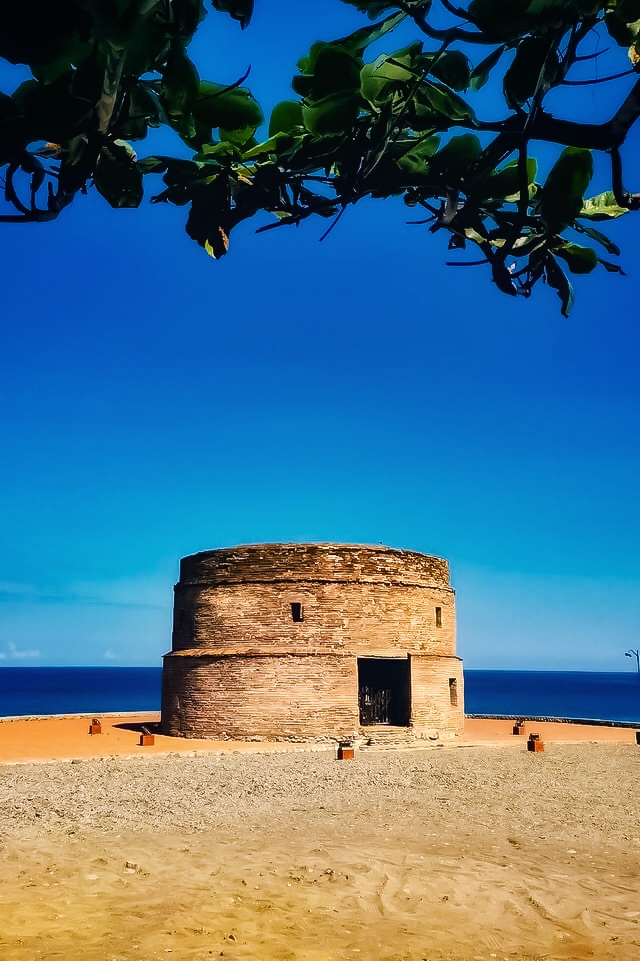 Restored brick Baluarte Watch Tower beside the pebble coast in Luna, La Union